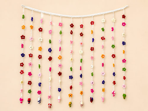 Blooming Welcome Handcrafted Crochet Floral Toran – rainbow mini flowers cascading from white header bar with miniature crochet figures at tips